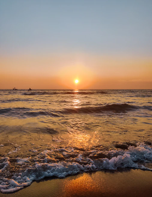 Sunset over a calm beach with tourists enjoying a guided kayak tour on crystal clear waters
