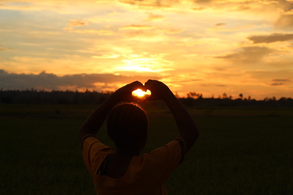 a person holding a baby in a field with the sun setting