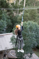 Adventure park zipline setup with safety harnesses and lush forest background.