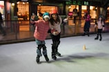 A young girl in skating gear smiling brightly on the ice rink.