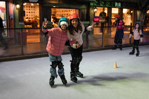 A young girl in skating gear smiling brightly on the ice rink.