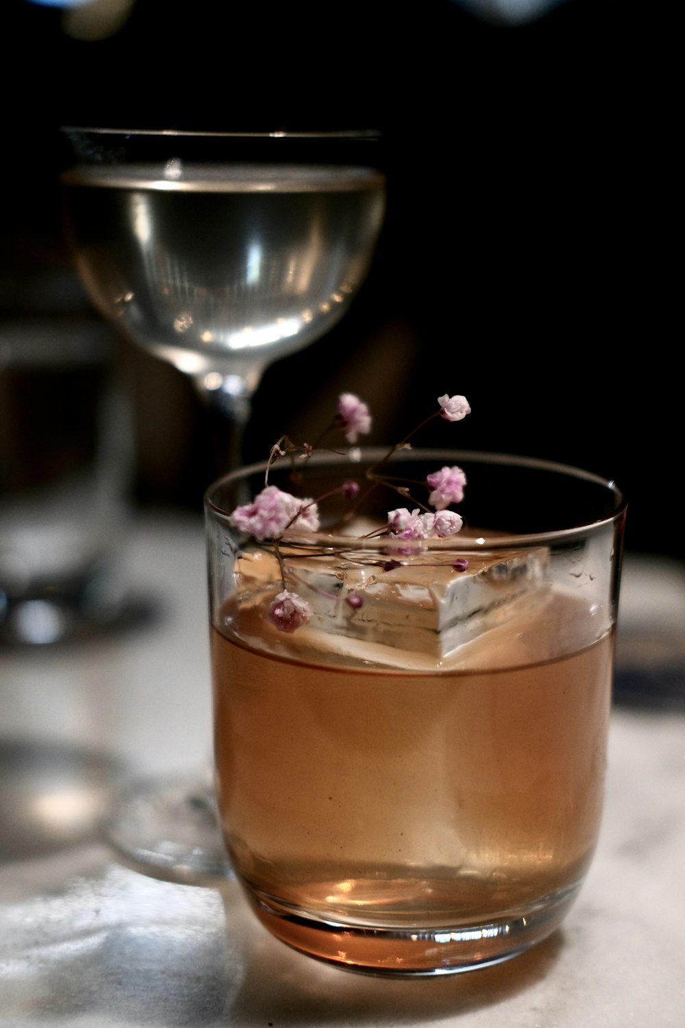 a glass of liquid with a flower in it