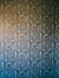 A sleek geometric art deco pattern with gold sunburst motifs on a deep navy background.