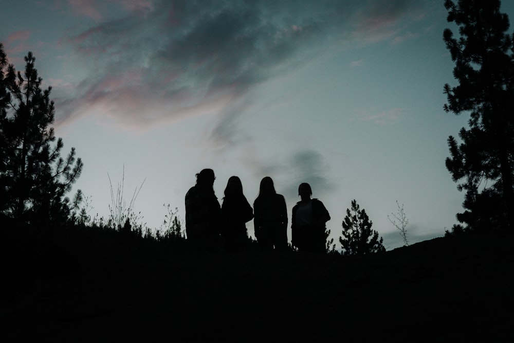 a group of people standing on a hill looking at the sunset