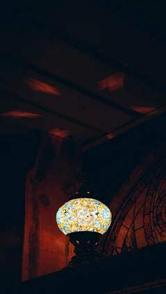 A glowing mosaic Turkish lamp casting colorful patterns on a warm beige background