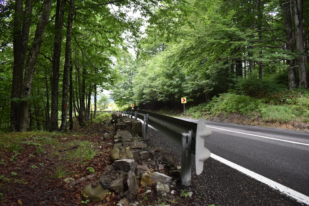 a road with a stone wall and trees on the side