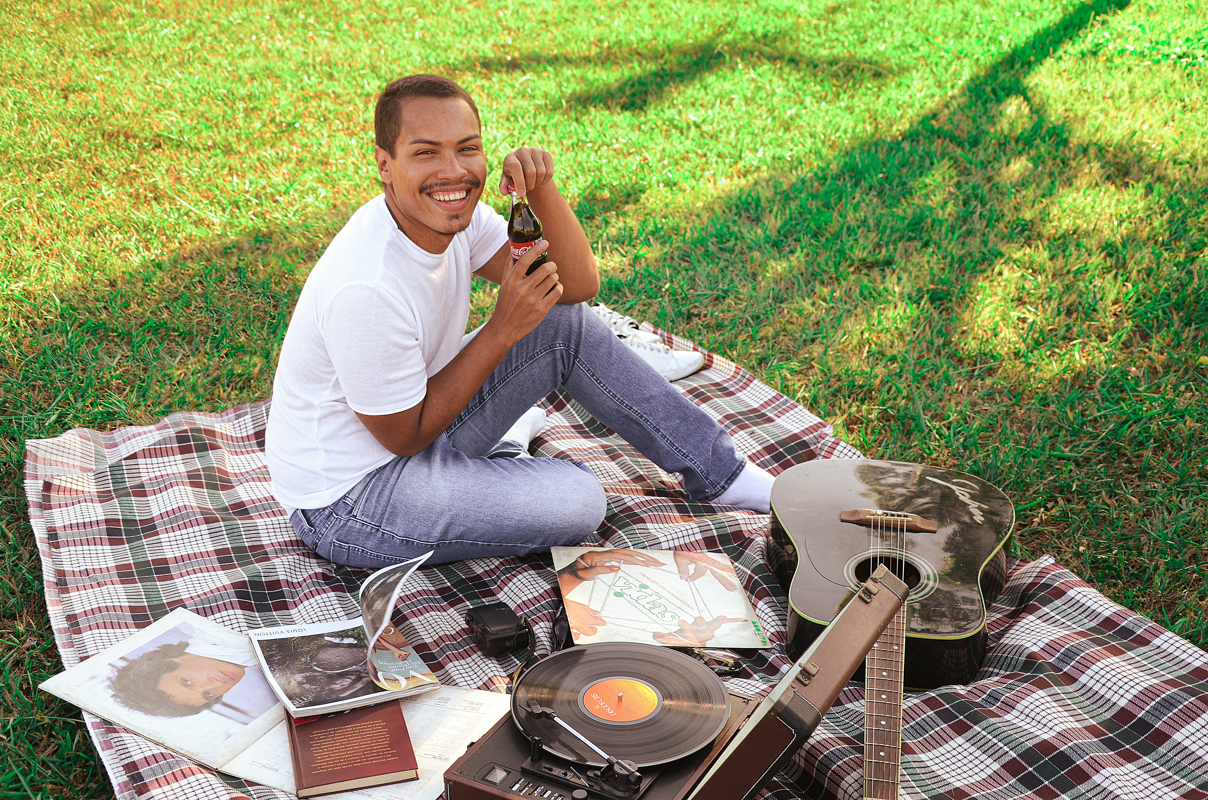 a person sitting on a blanket with a guitar and a record player