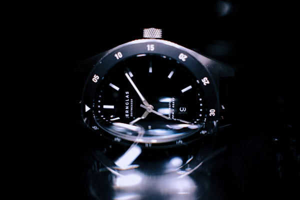 Close-up of a sleek stainless steel men's wristwatch with a black dial and luminous hands.