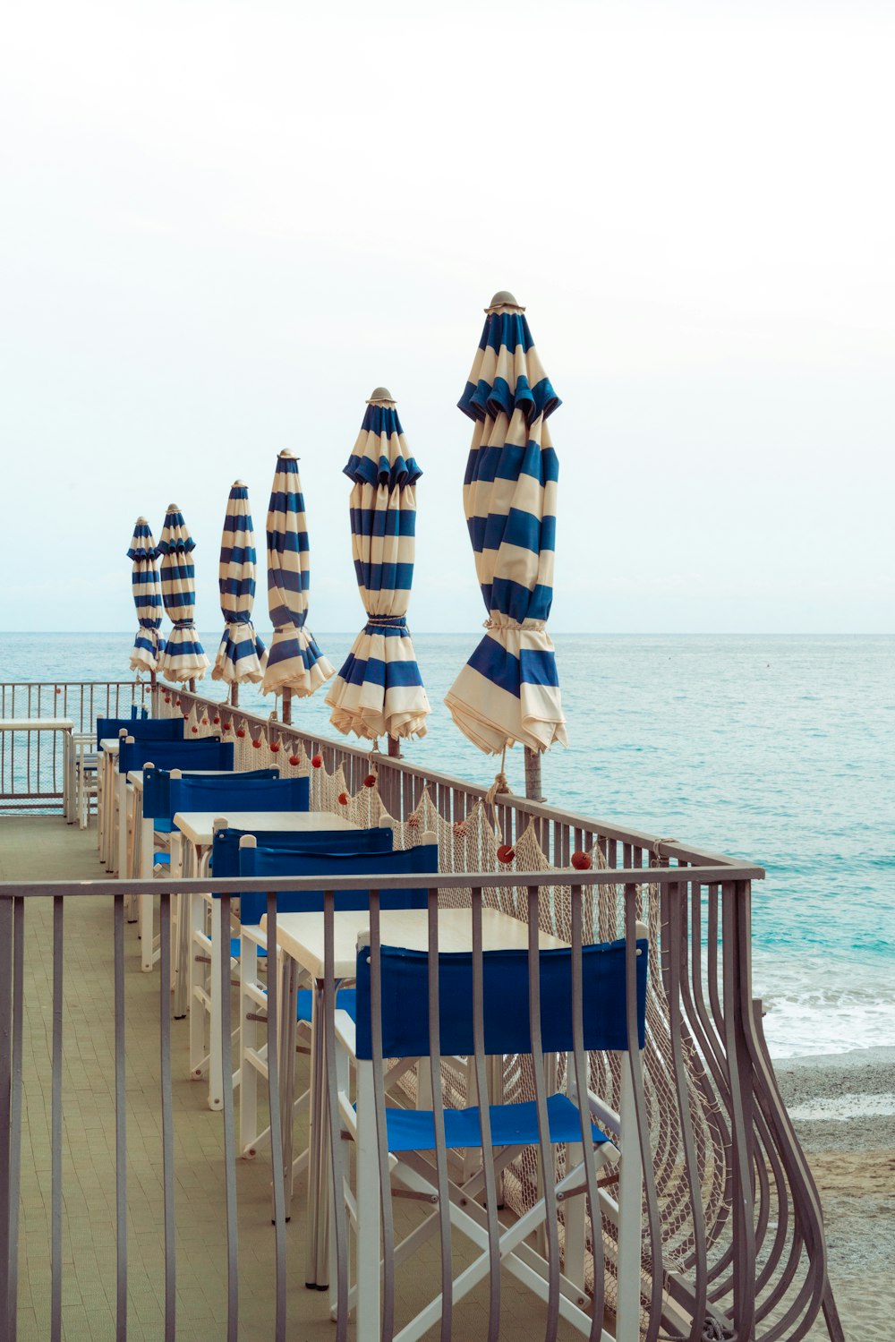 a deck with chairs and umbrellas on it by the water