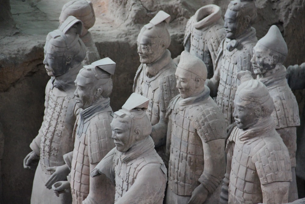 um grupo de pessoas usando chapéus brancos com o Exército de Terracota ao fundo