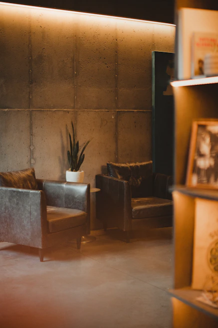 A modern interior with a sleek leather armchair beside a tall floor lamp and minimalist bookshelf.