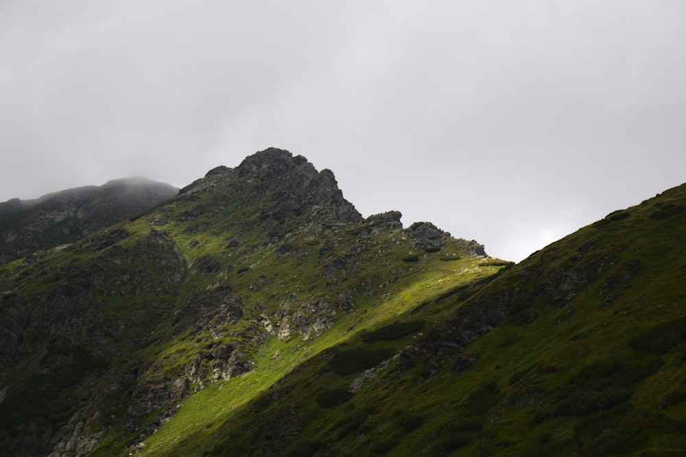 a grassy mountain with a foggy sky