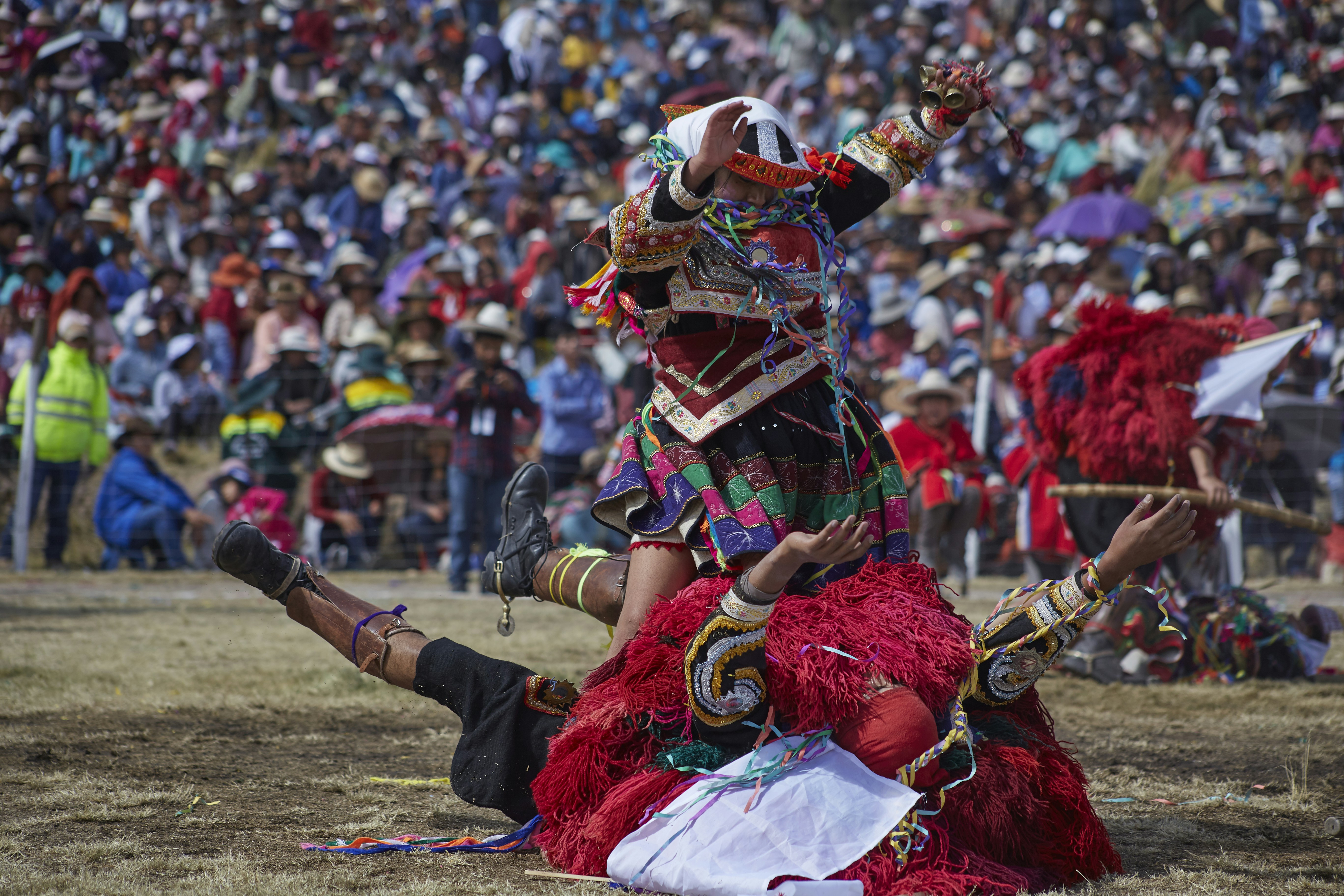 a person in a garment holding a sword in front of a crowd