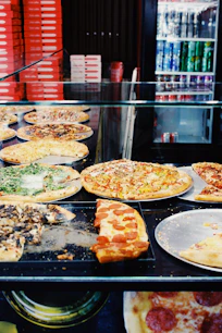 a display case with pizzas