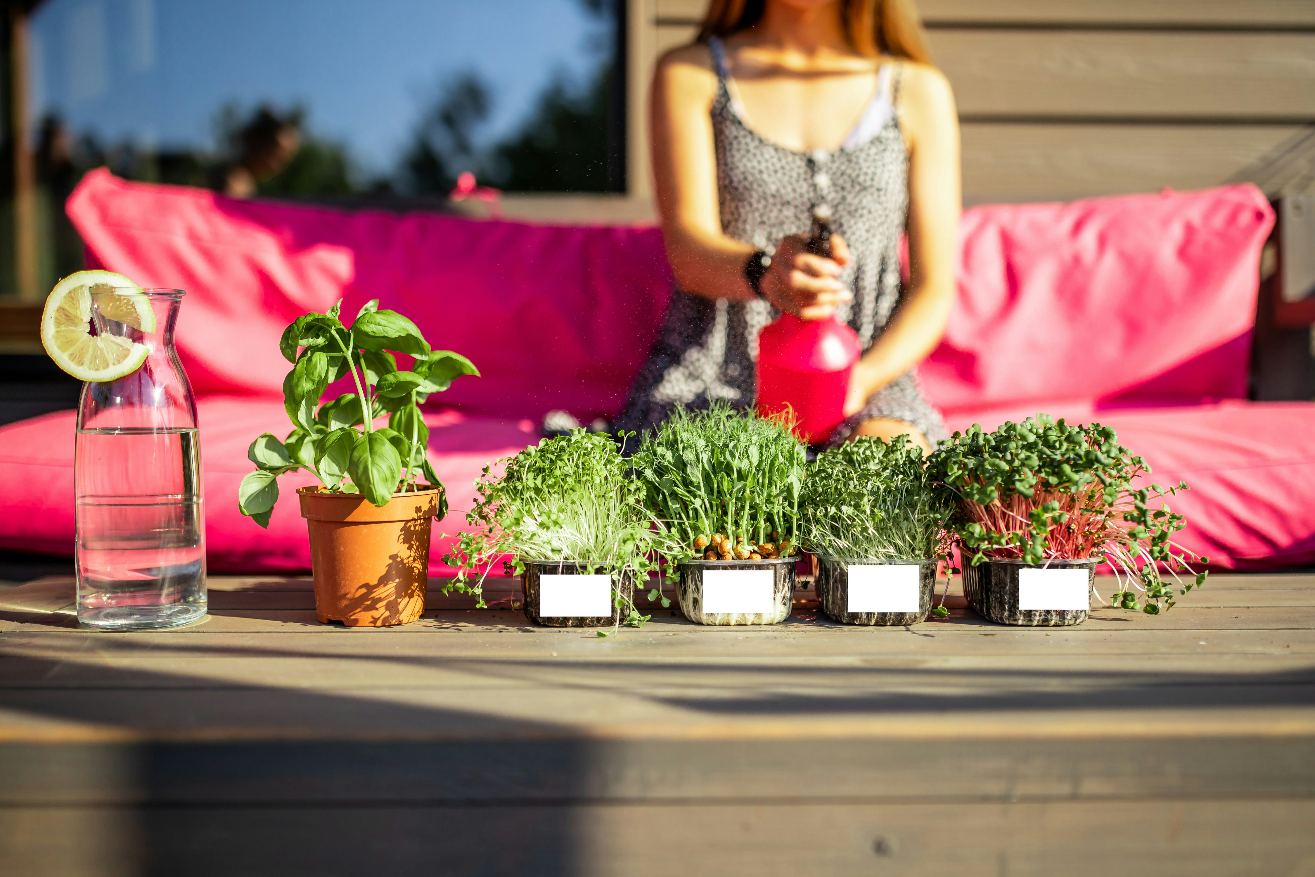 a woman standing next to a table with plants and a vase