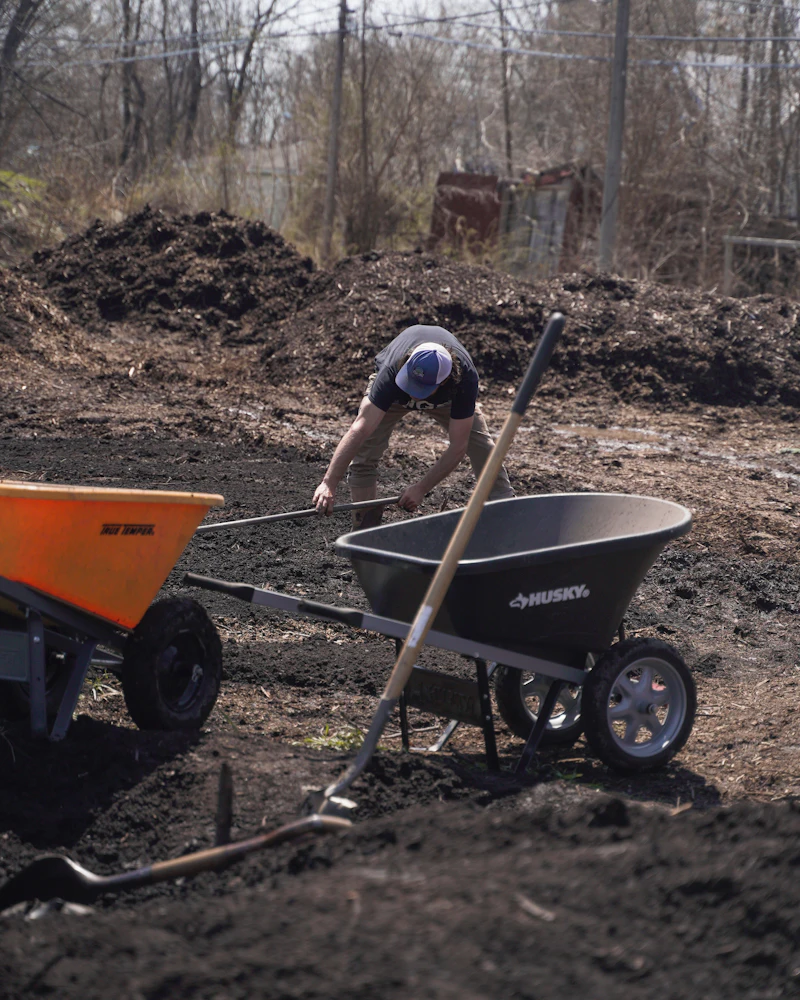 A gardener kneeling and digging in garden soil