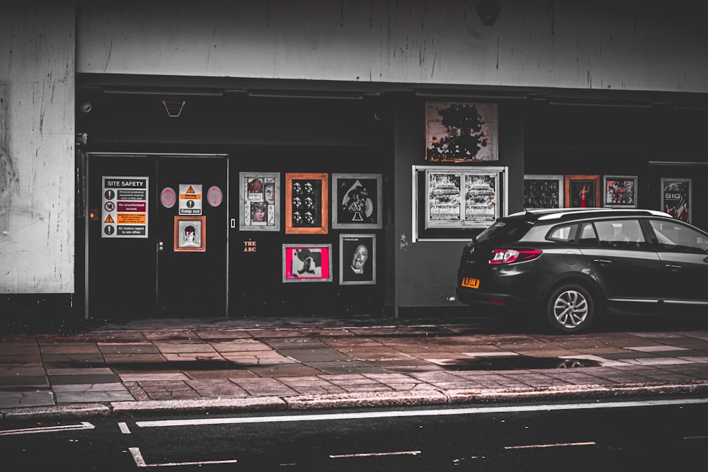 a car parked in front of a building with posters on the wall