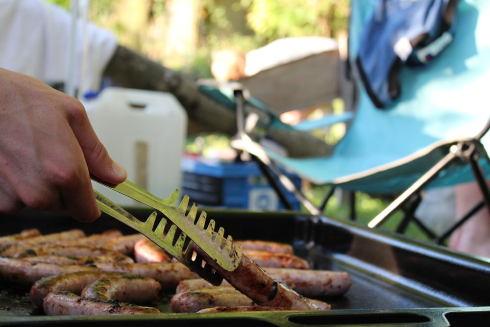 a person holding a knife over a pile of cooked fish