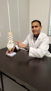 A caring doctor gently examining a patient's spine in a bright, modern clinic room.