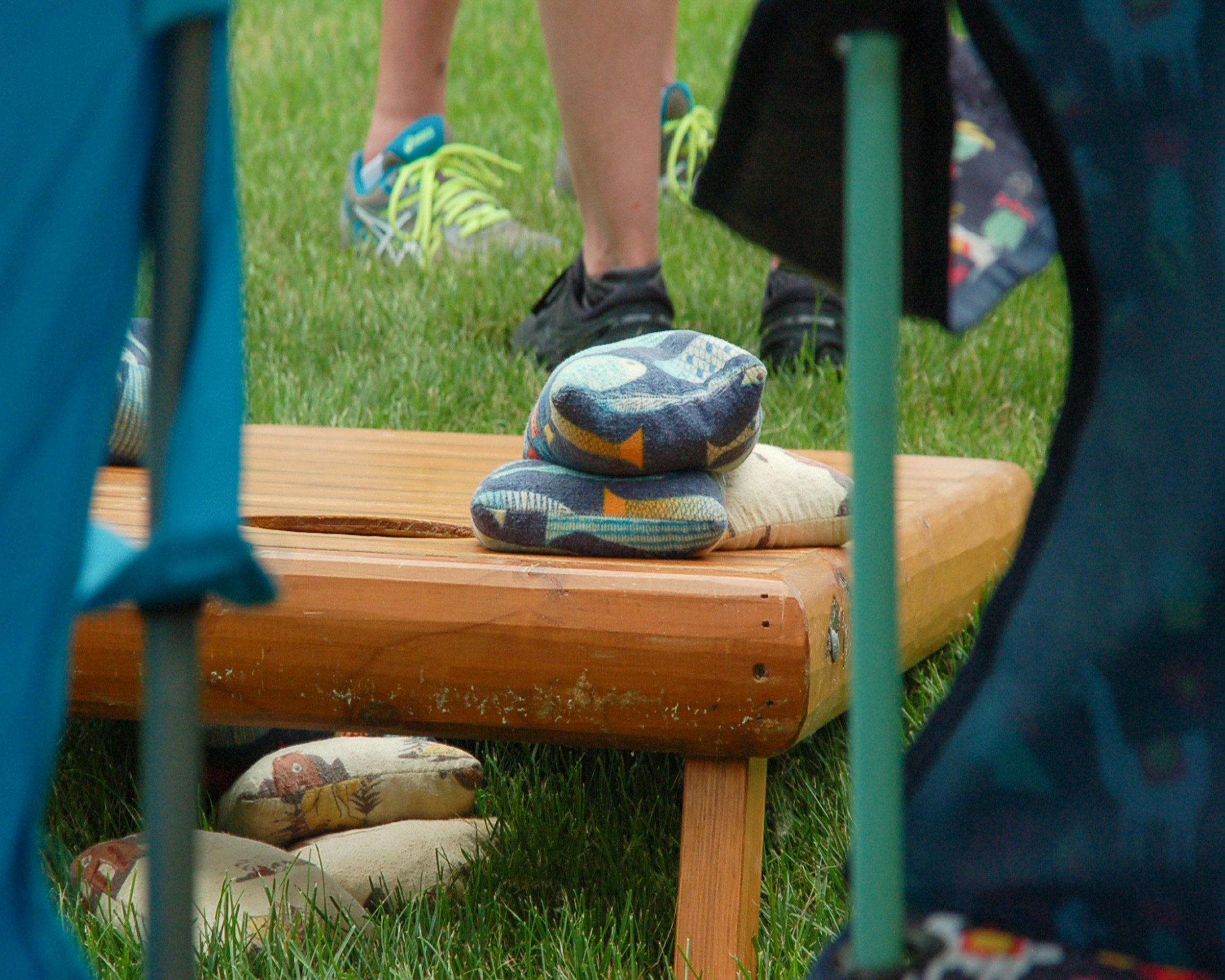 person playing cornhole on a grass surface outdoors