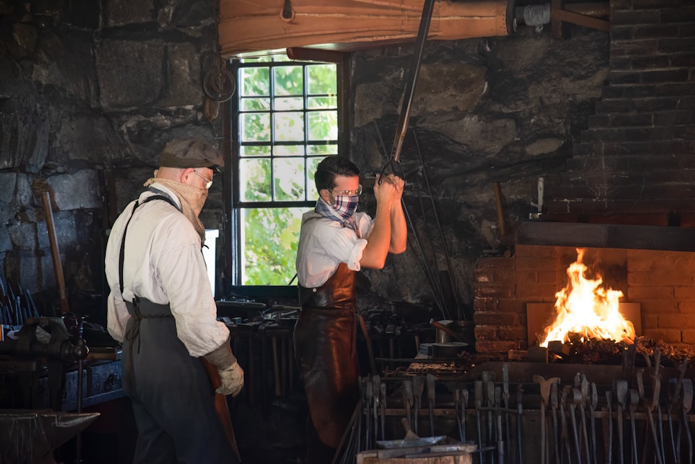 a couple of men working in a brick room with a fire