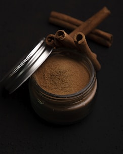 a metal cup with a brown substance and a metal spoon