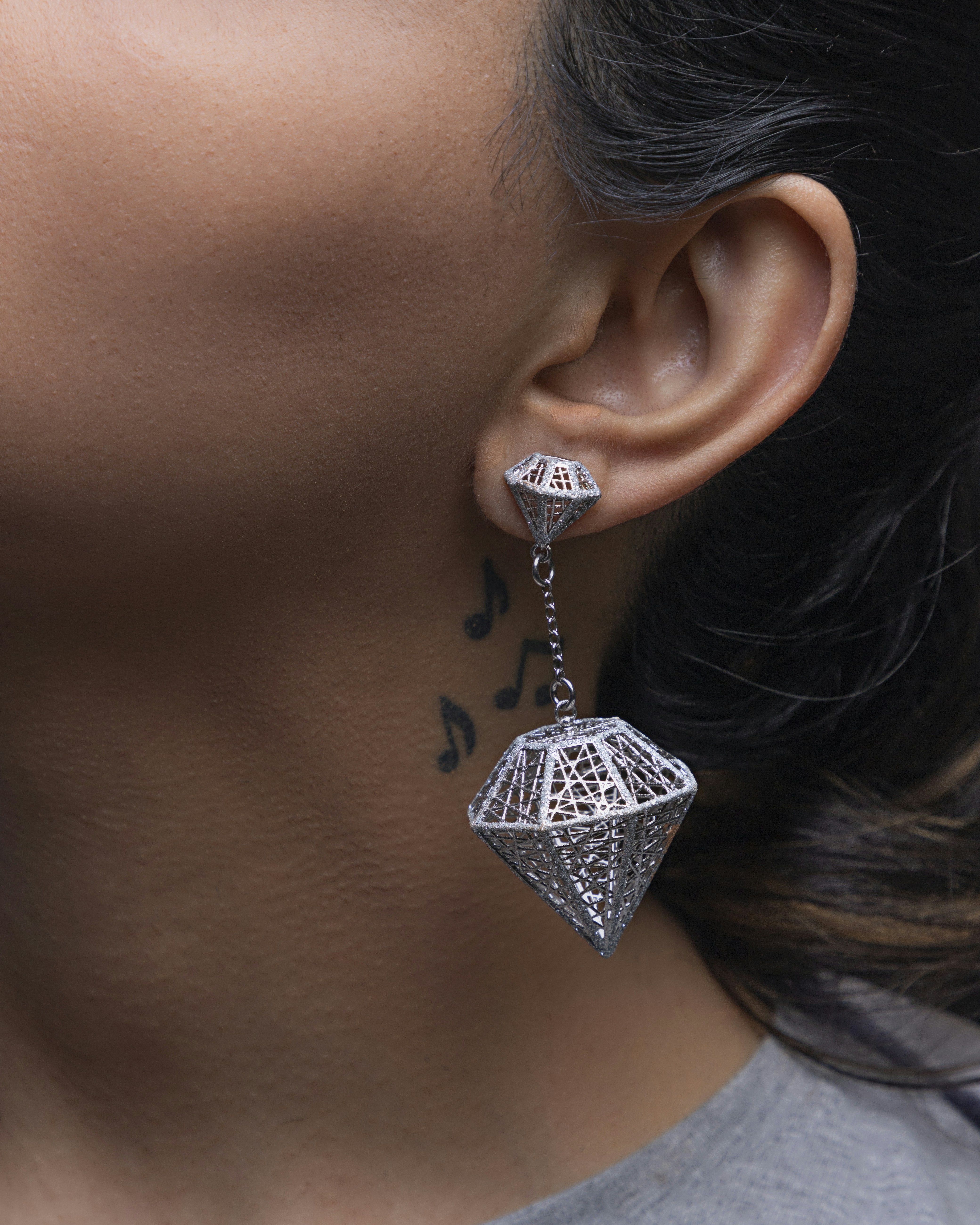 a woman's ear with a necklace and a diamond pendant