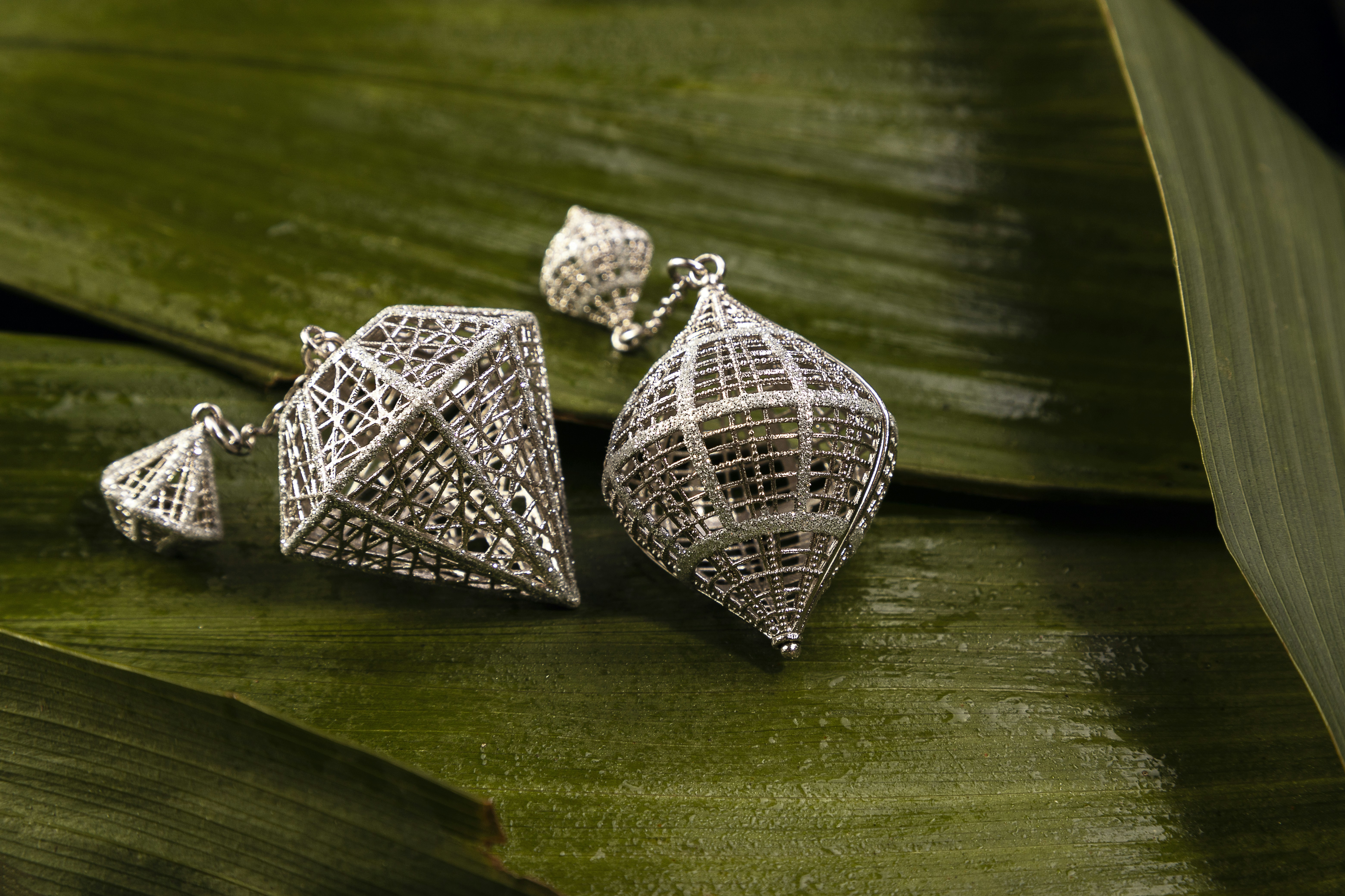 Delicate handcrafted silver leaf drop earrings on white velvet