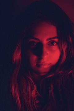 Close-up of a sultry model bathed in crimson light with smoky plum shadows.