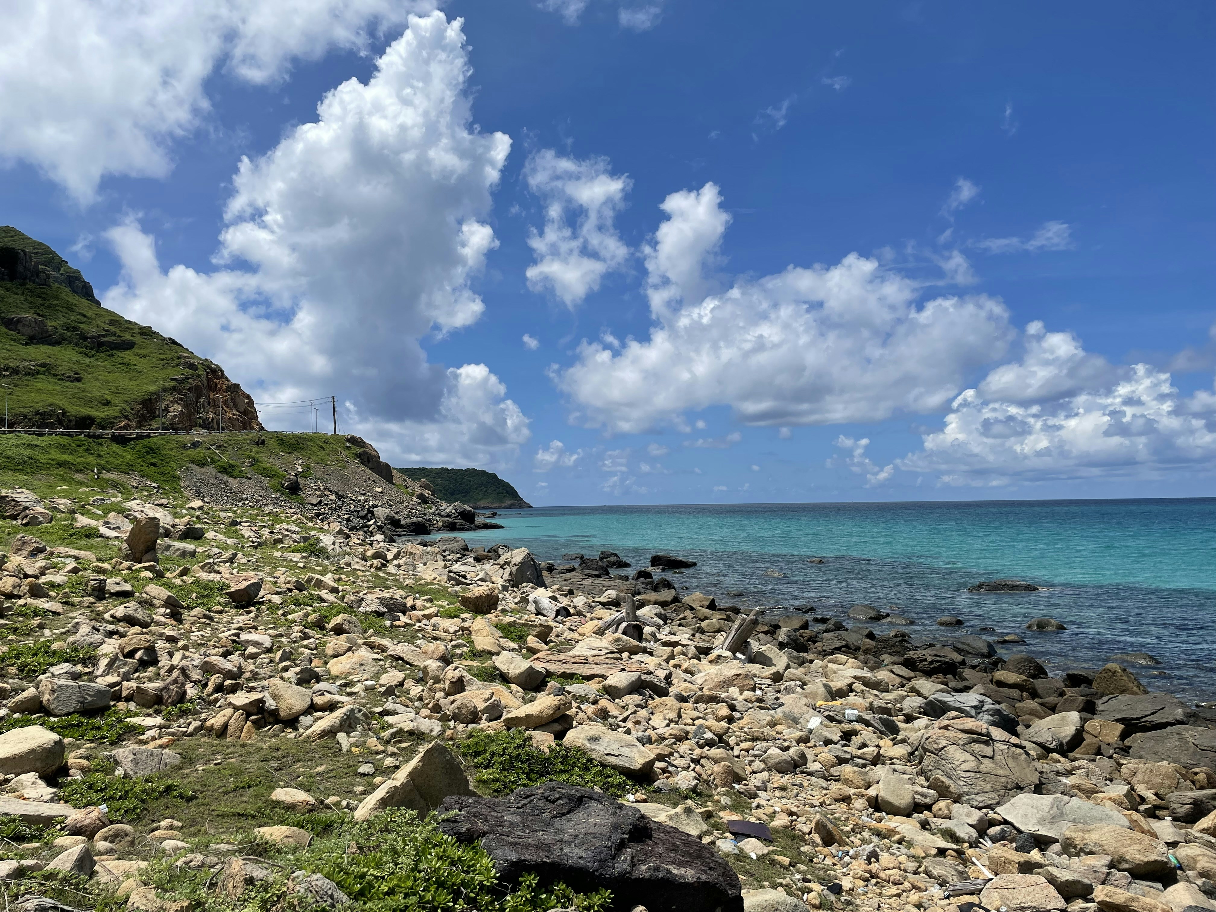 a rocky beach with a body of water in the background, 