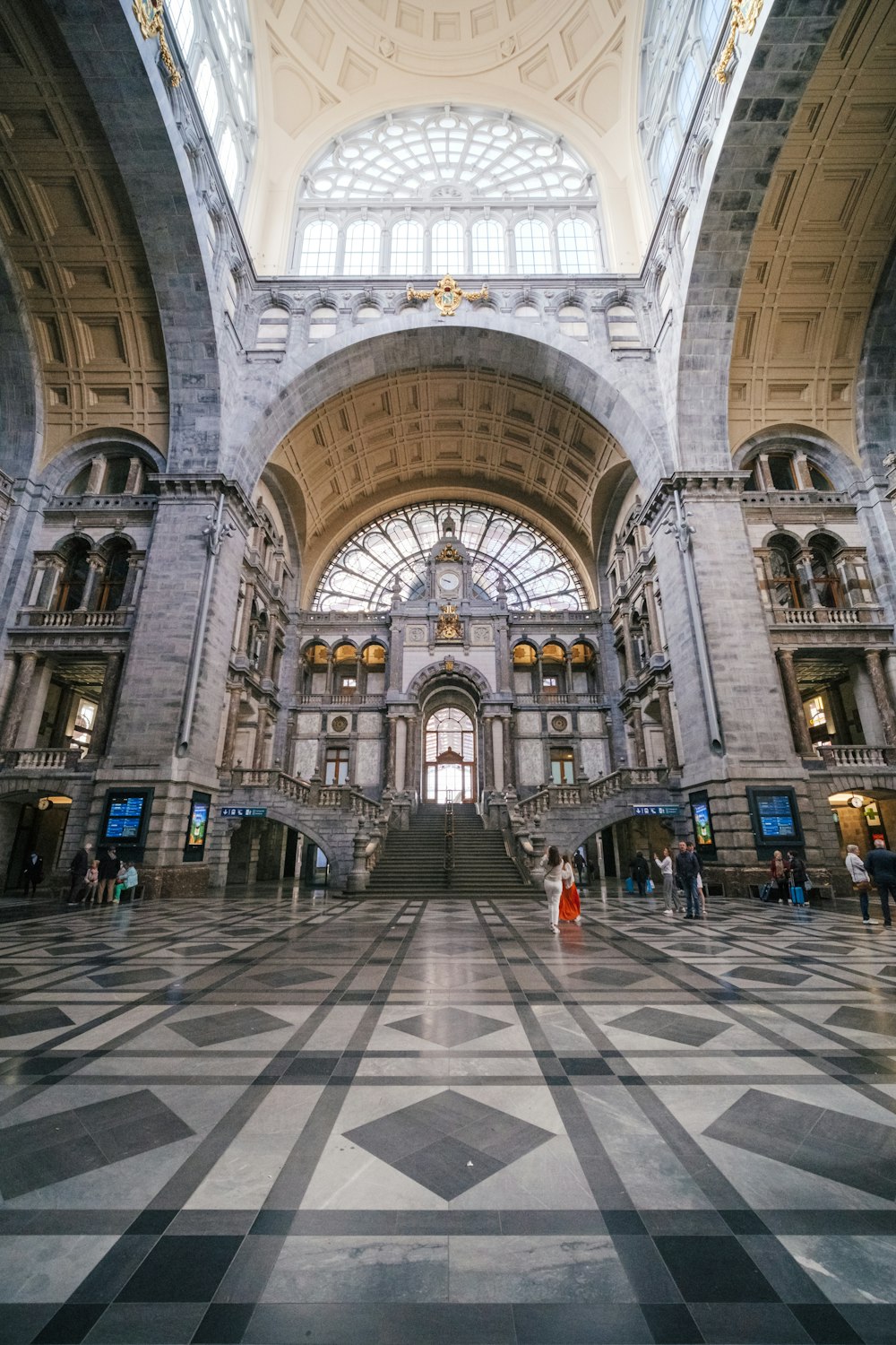 a large building with a large arched ceiling and many people walking around