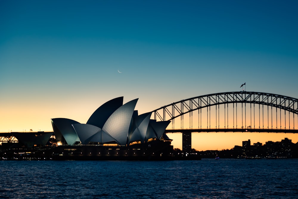 Sydney Opera House over water with a city in the background