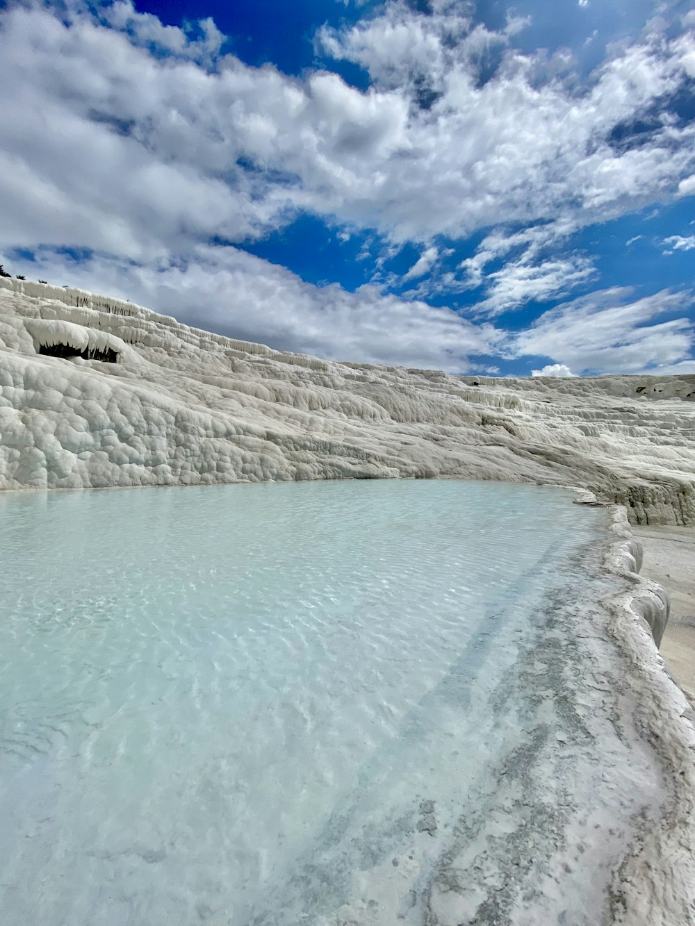 a body of water with a rocky shoreline and a blue sky