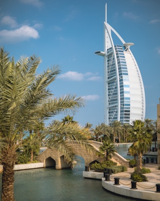 a tall building by the water with Burj Al Arab in the background