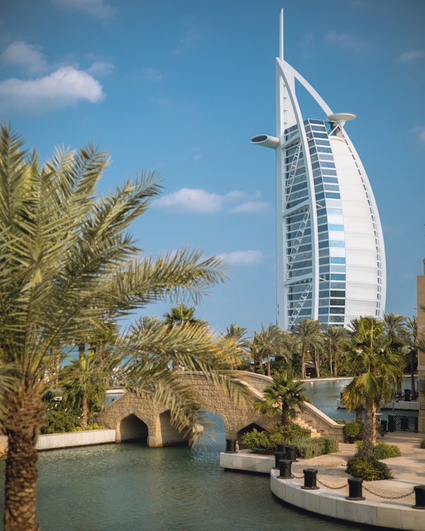 a tall building by the water with Burj Al Arab in the background