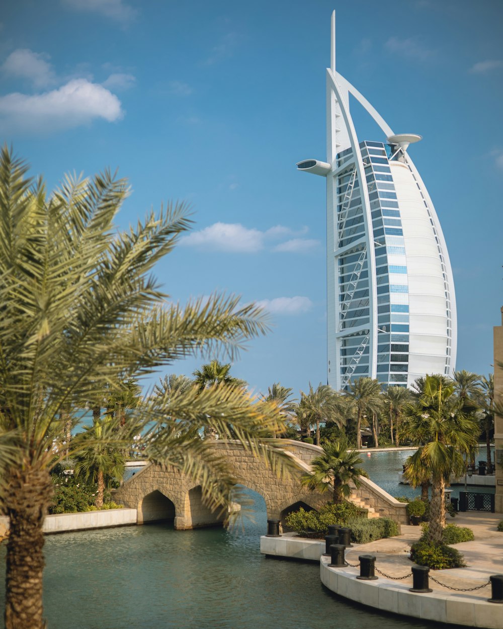 a tall building by the water with Burj Al Arab in the background