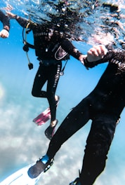 A scuba instructor guiding a student underwater during an open water dive.