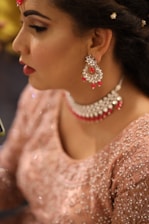 Close-up of a confident woman wearing elegant semi-jewelry in deep burgundy and muted green tones.