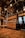 The interior features wooden flooring and cabinetry, elaborate ceiling decorations, and metallic handrails with grips attached. Display cabinets with decorative items are visible, alongside intricately designed glass doors.