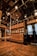 The interior features wooden flooring and cabinetry, elaborate ceiling decorations, and metallic handrails with grips attached. Display cabinets with decorative items are visible, alongside intricately designed glass doors.