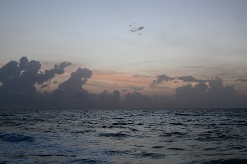 Ocean waves crashing under a twilight sky filled with stars.