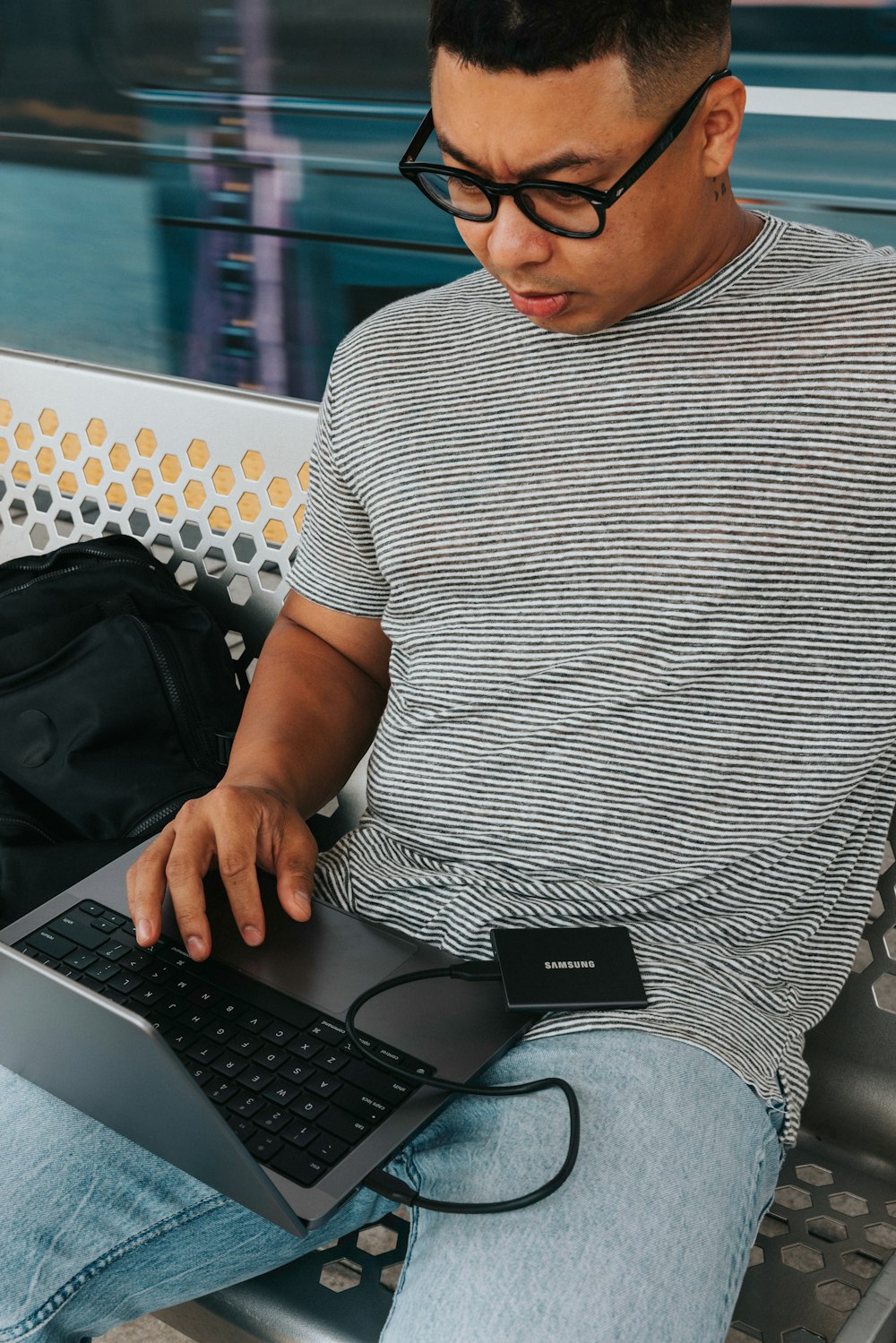 a man sitting on a bench with a laptop