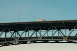 A pink steel logistics truck crossing a bridge over a river, symbolizing connection and movement.