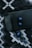 A black electronic device lies on a patterned fabric surface alongside three blue Samsung SD cards. The fabric has a geometric design in shades of black, white, and gray.