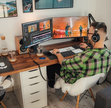 a person sitting at a desk with a computer and a dog