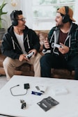 a couple of men wearing headphones and sitting on a couch