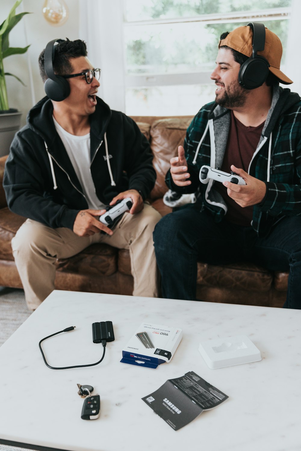 a couple of men wearing headphones and sitting on a couch