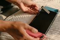 Technician using compressed air to remove dust buildup from a game console's vents.