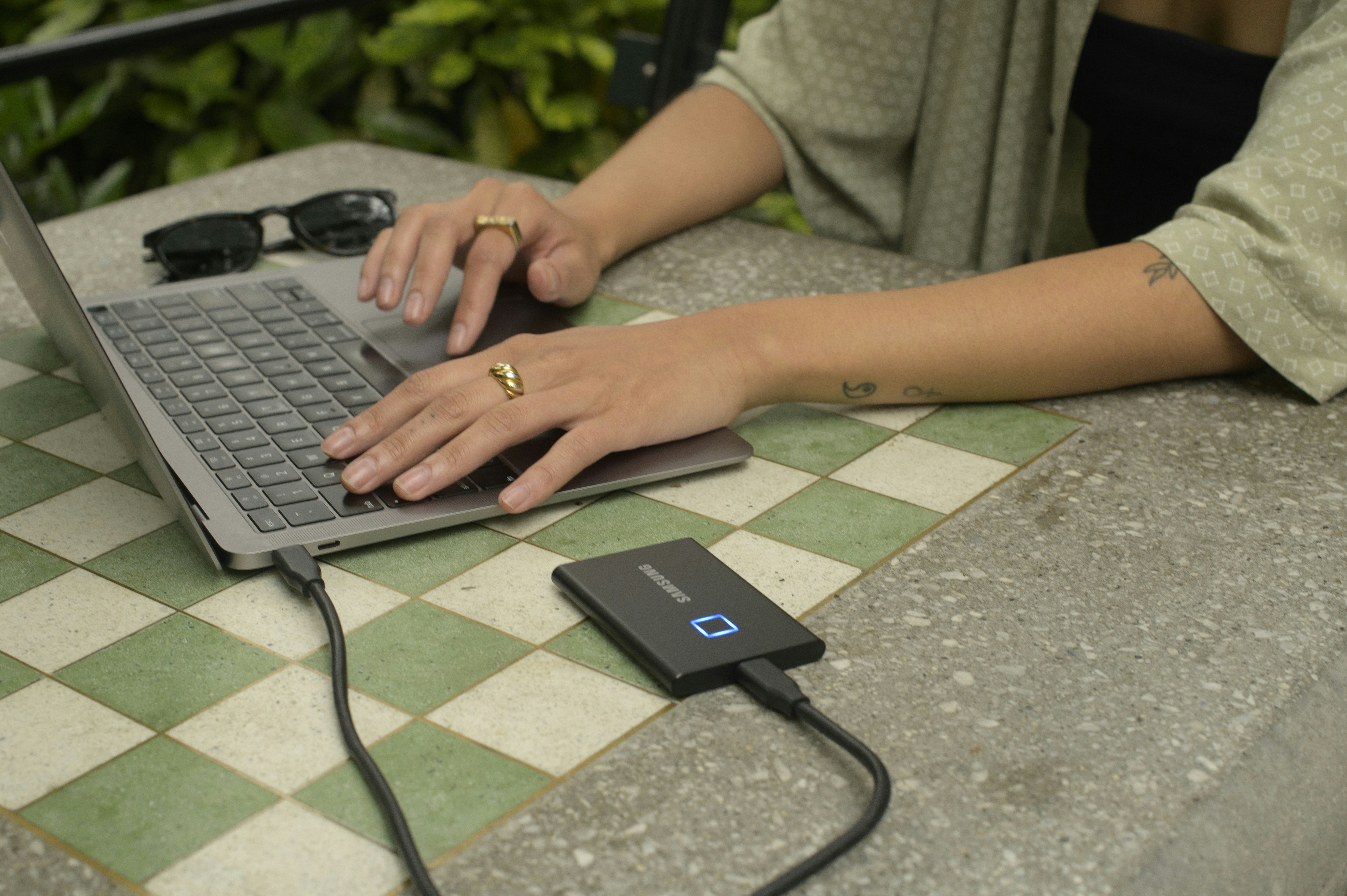 Person maintaining laptop with compressed air cleaning keyboard vents and using charge limiter software