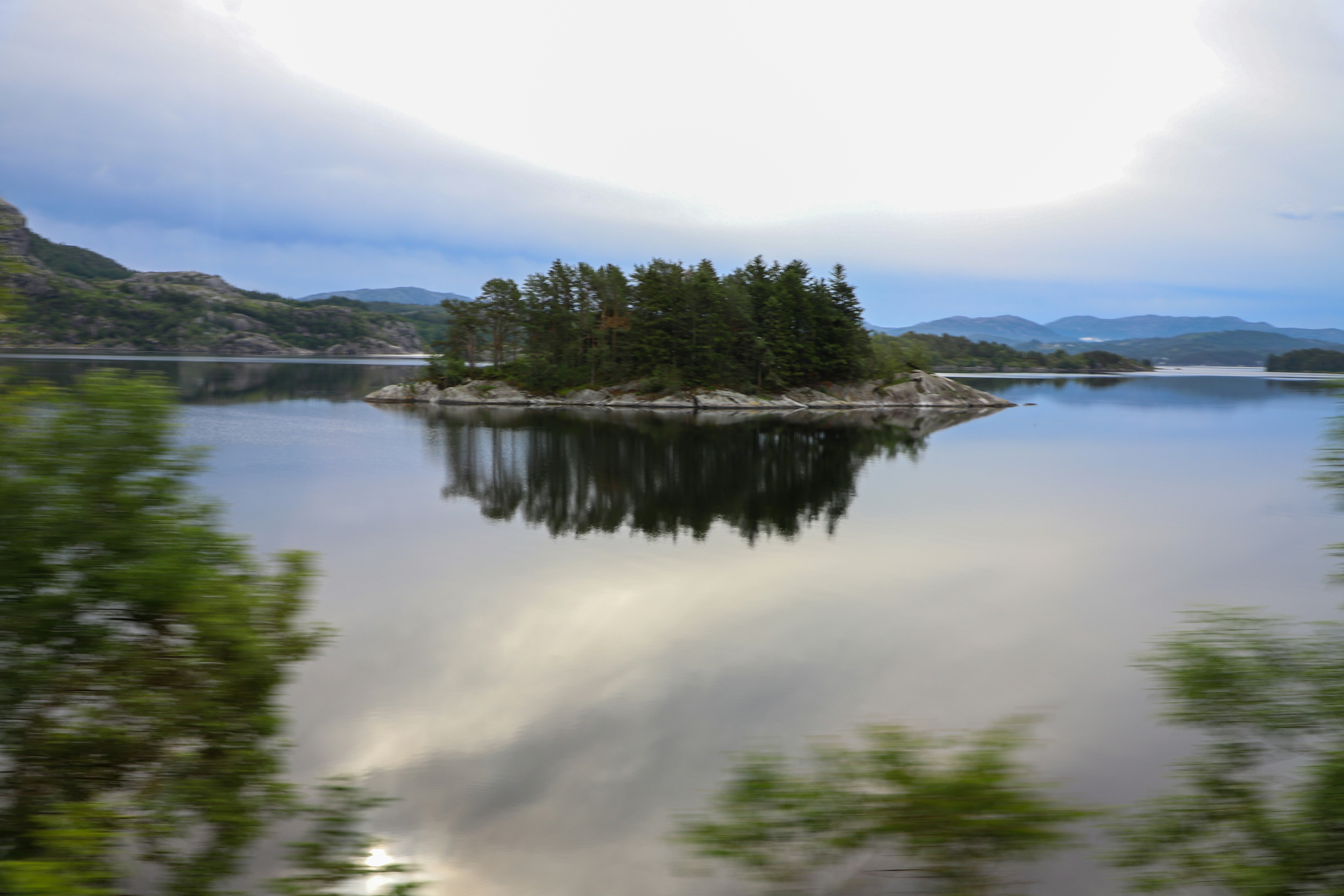 a body of water with trees and hills in the background